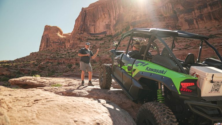 A man next to a green UTV, embarking on an epic 4x4 adventure in the wilderness.