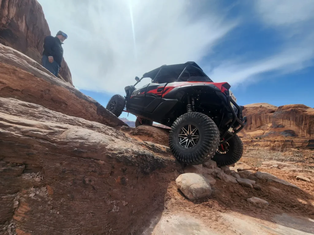 A man standing on a rock in front of a UTV during a scenic sunset tour in Moab.