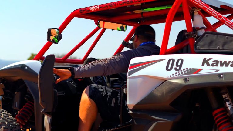 A man skillfully maneuvers a Kawasaki ATV along a rugged dirt road, showcasing his adventurous spirit.