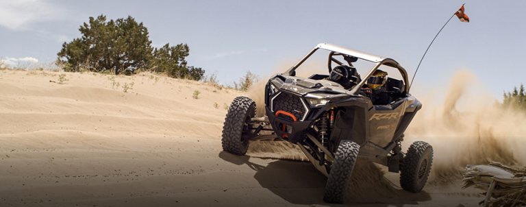 A black off-road vehicle speeding on a sandy track with motion blur effect.
